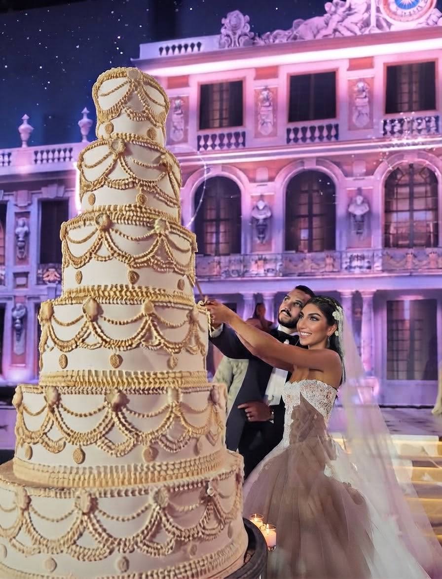 Arab wedding celebration with a couple beside a grand multi-tiered wedding cake